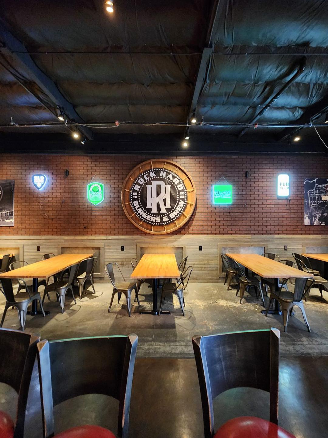 Dining room interior with the Rock Hard Burgers & Brew logo on a brick wall in Citrus Heights