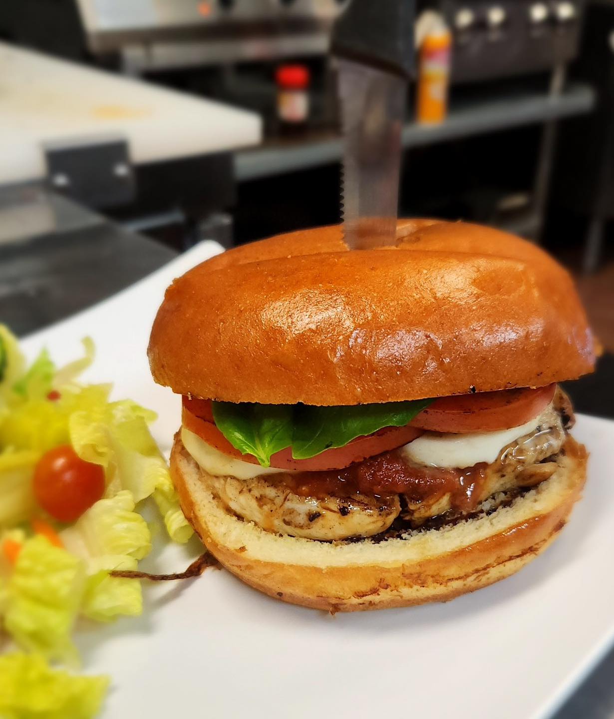 Grilled chicken sandwich on a brioche bun with side salad