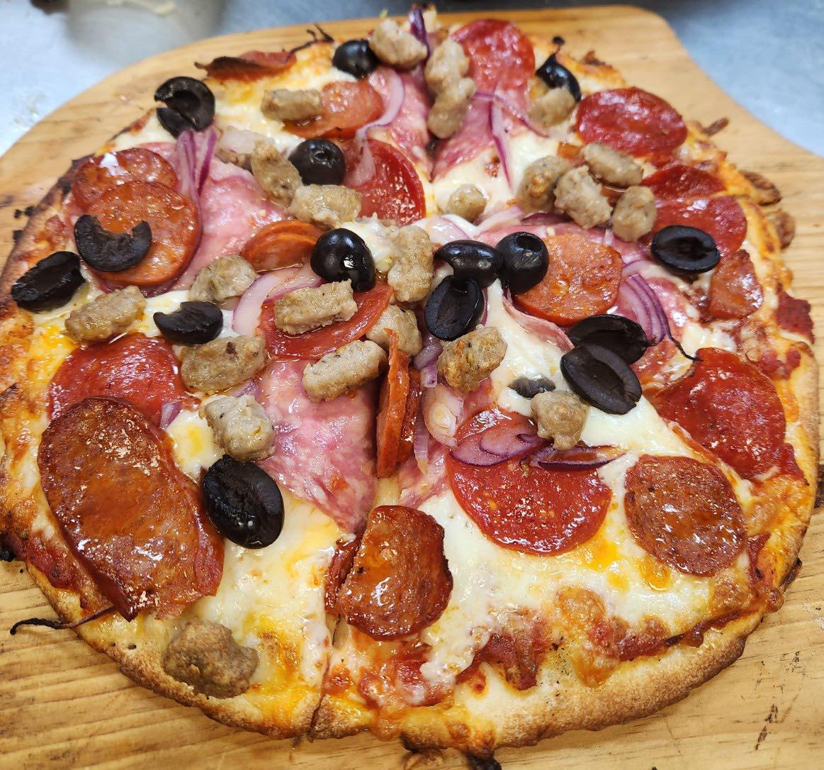 House pizza with pepperoni, sausage, red onion, and olives on a Tuscany crust