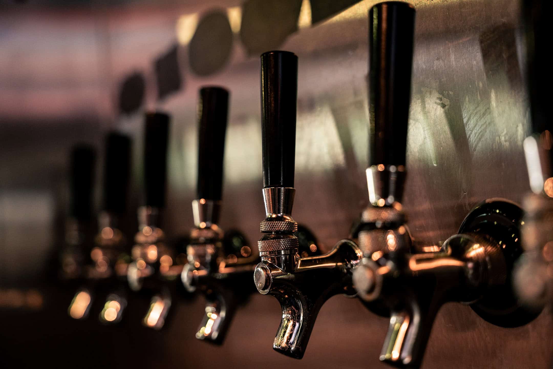 Cold beer taps lined up at the Rock Hard Burgers & Brew bar